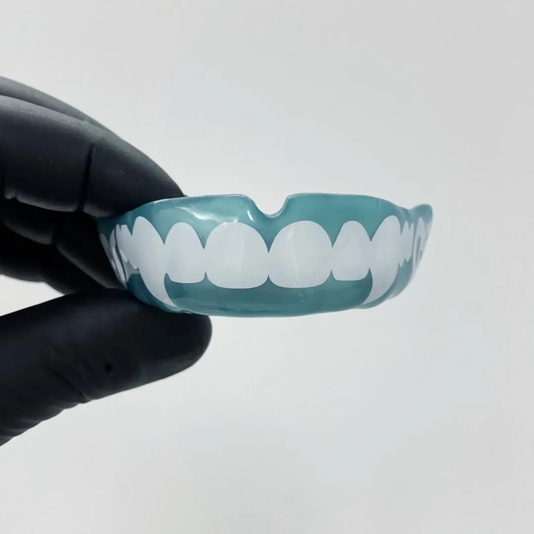 A teal custom sports mouthguard with white fang artwork.
