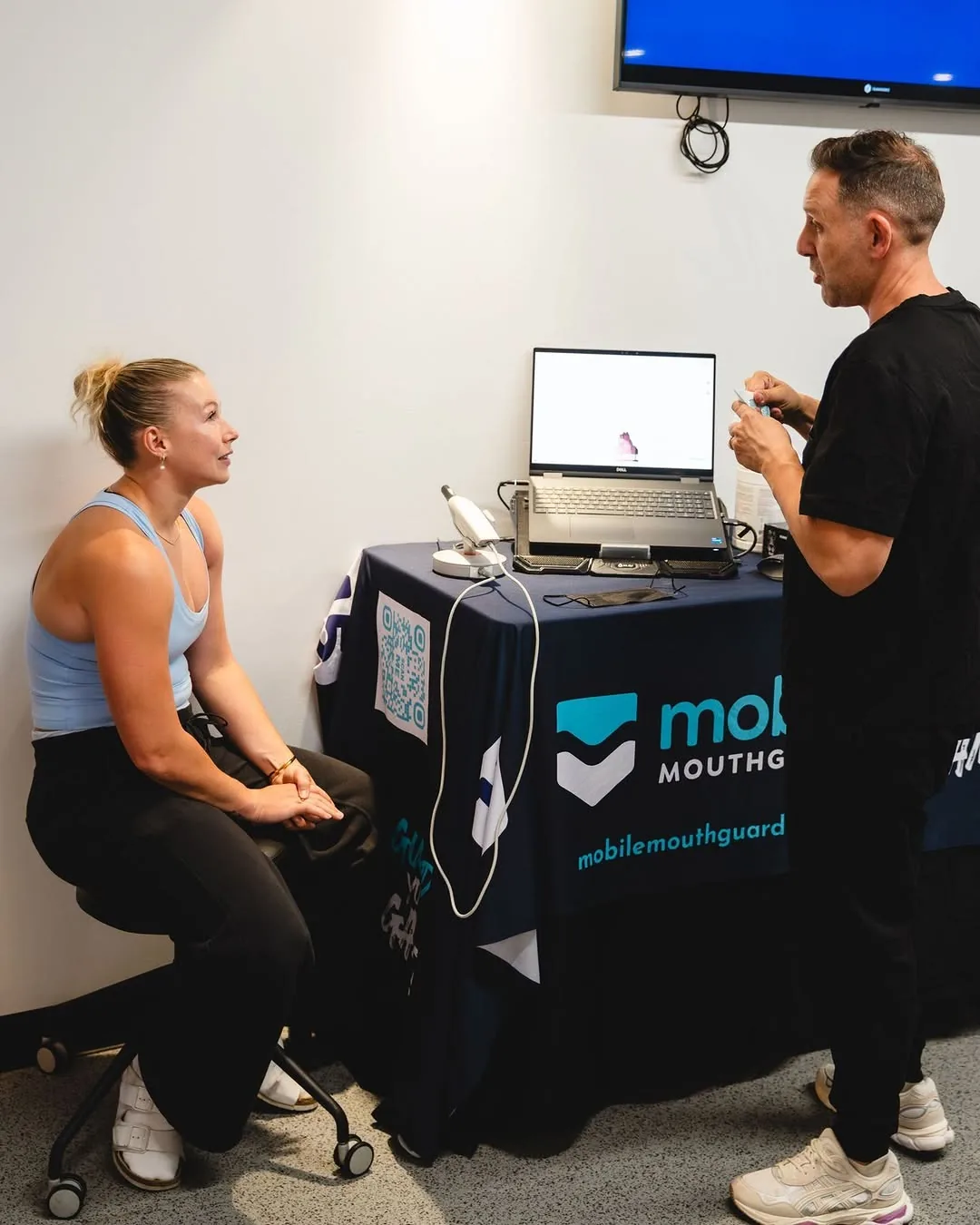 A player sits by the portable scanning table while the technician talks her through the scan.