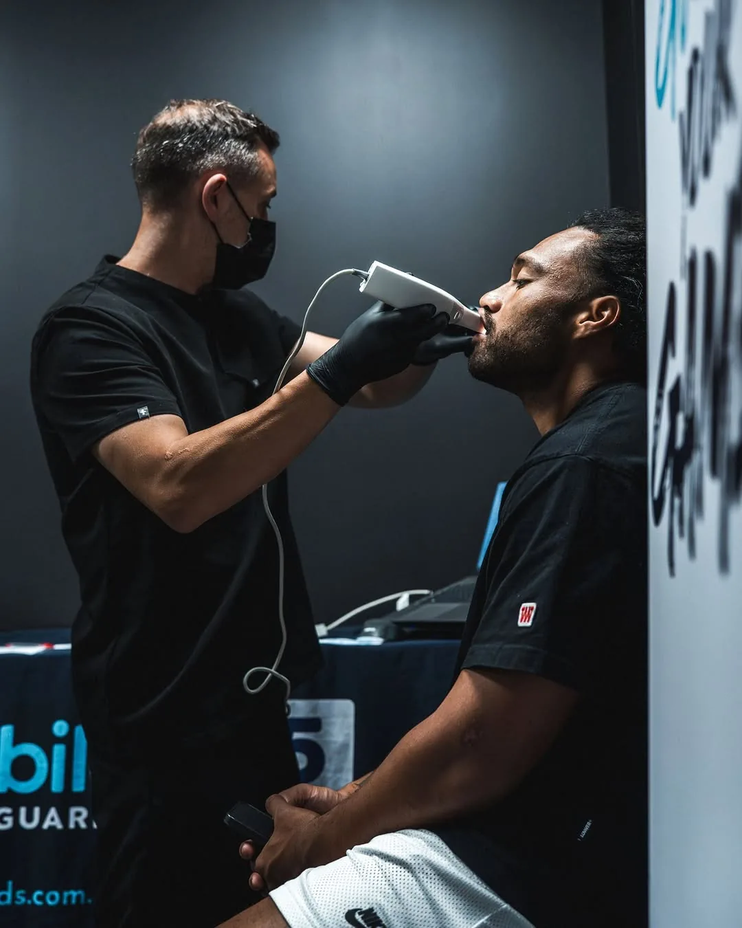 A technician scans a seated player's teeth with a handheld 3D scanner.